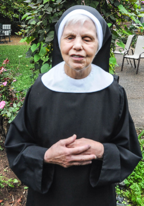 Sister Dolores pictured in her habit with her hands clasped in her convent's garden