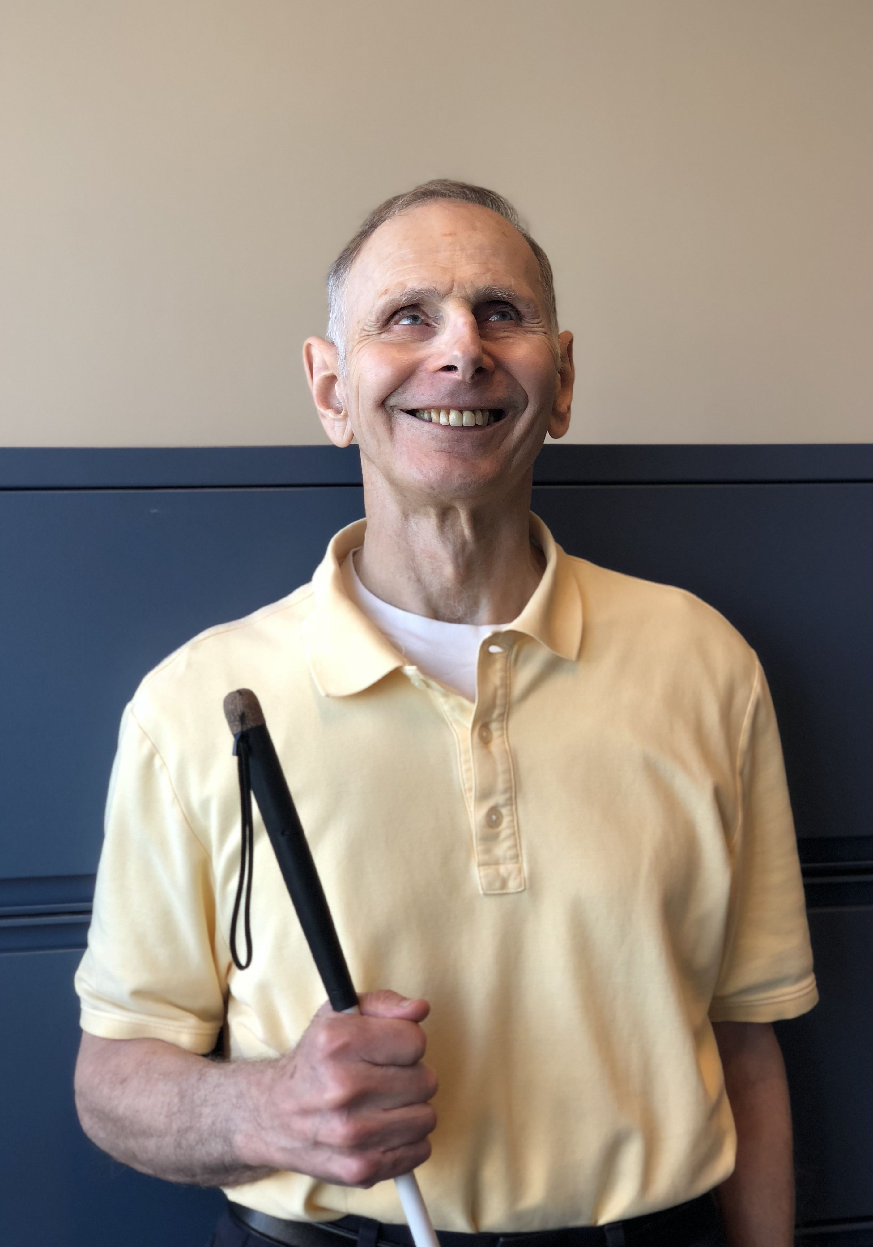 Dr. Ticchi wearing a yellow shirt and smiling in front of some filing cabinets