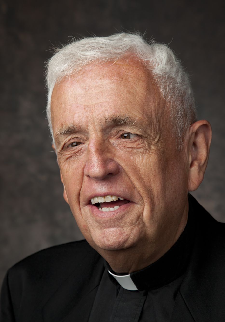 Head shot of Father Larry smiling in a black shirt and collar
