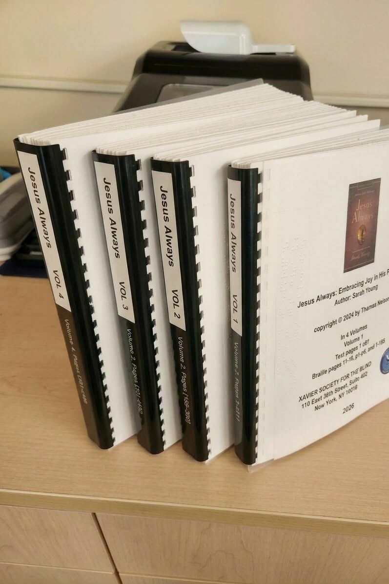 Four volumes of braille standing upright on the counter