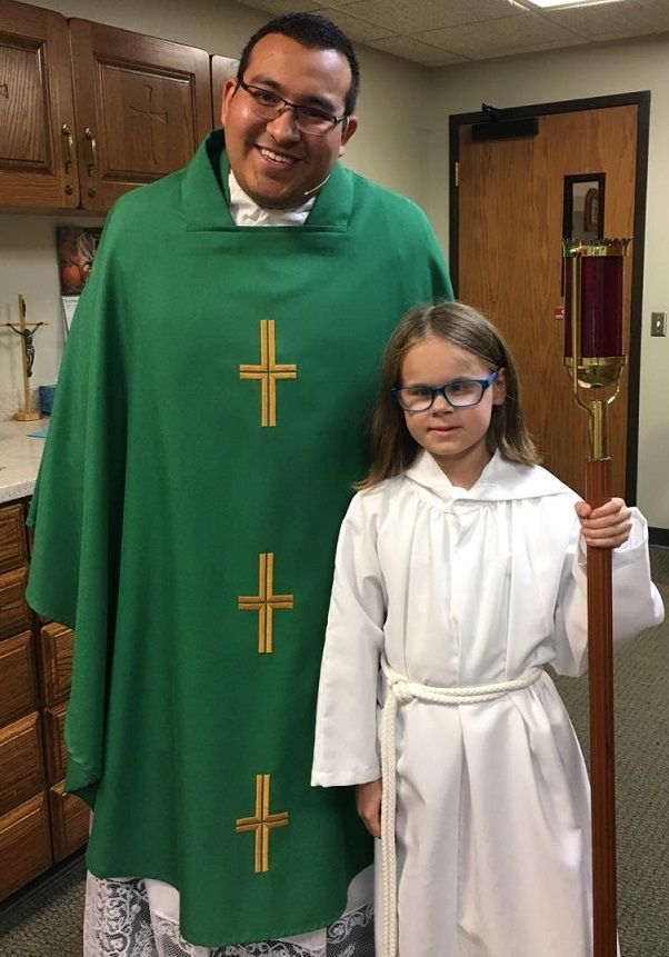 Mara with her parish priest after serving her first Mass