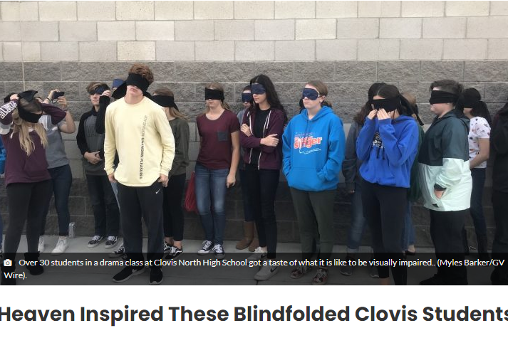 A picture of a bunch of students against a wall wearing blindfolds
