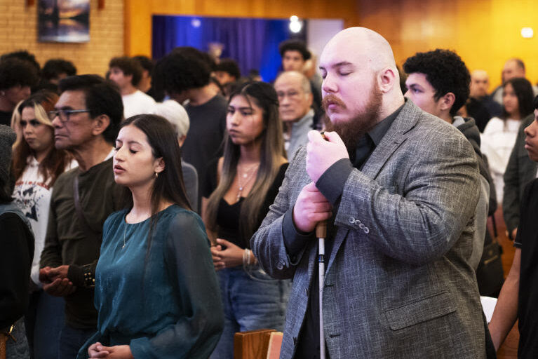 Ryan pictured at Mass with other parishioners. He is pictured with his white cane wearing a suit.