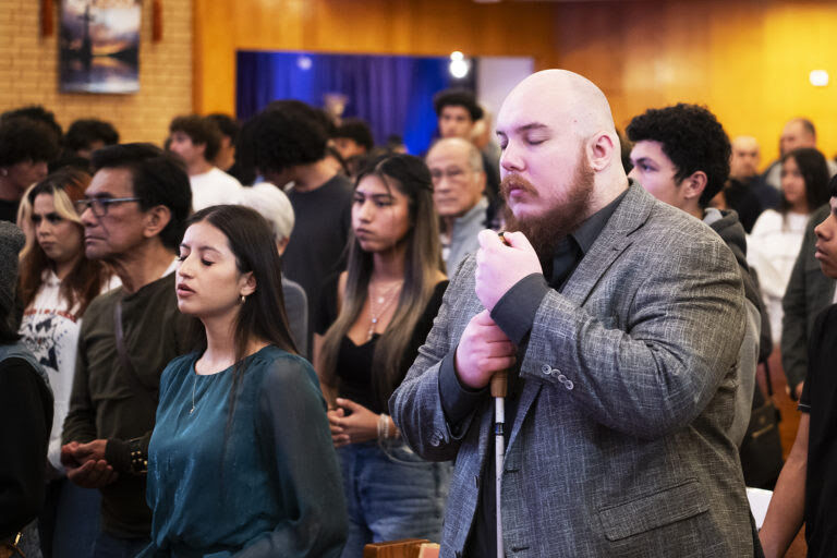 Ryan pictured at Mass with other parishioners. He is pictured with his white cane wearing a suit.