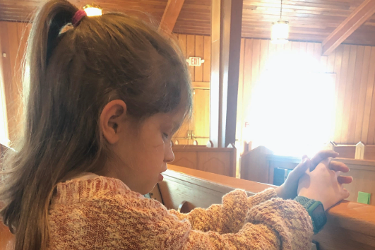 Screenshot of the article showing Kaydence praying inside her church